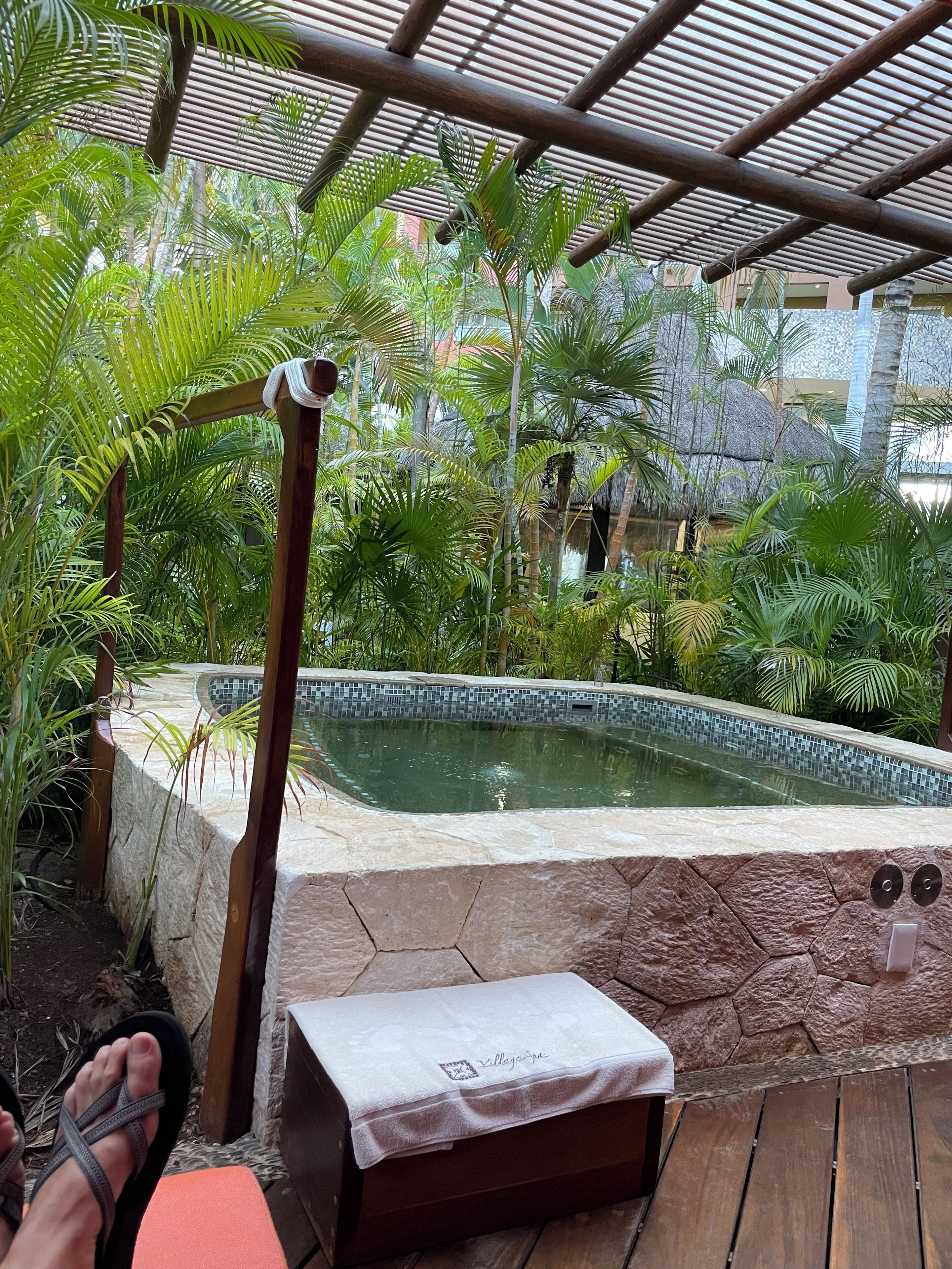 Un espace piscine bordé de pierres, entouré d’une végétation luxuriante et agrémenté d’une pergola en bambou.