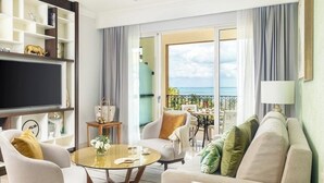 A living room with a flat-screen TV, a ceiling fan, a sofa, a coffee table, and a balcony with a view of the sea. -  Suite with Tranquil vibes, beautiful panorama of sea in fabulous Quintana Roo (quintana roo)
