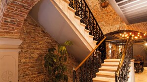 Una escalera con pared de ladrillo, plantas en macetas y un candelabro.