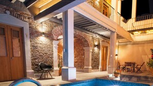 Una piscina con una escalera de metal, rodeada de muros de piedra y una puerta de madera.