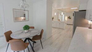 Una cocina moderna con armarios blancos, una isla central y una zona de comedor con una mesa redonda y sillas.