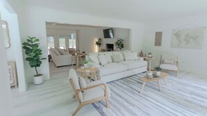 Una sala de estar moderna con un sofá, sillones, una mesa de centro y un televisor.