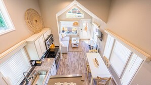 A compact kitchen with a dining area, a sofa, and a TV. - Rainforest Tiny Home Retreat: Coastal (Forks)