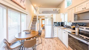 A modern kitchen with a central island, white cabinetry, and a stainless steel refrigerator. - Rainforest Tiny Home Retreat: Industrial (Forks)