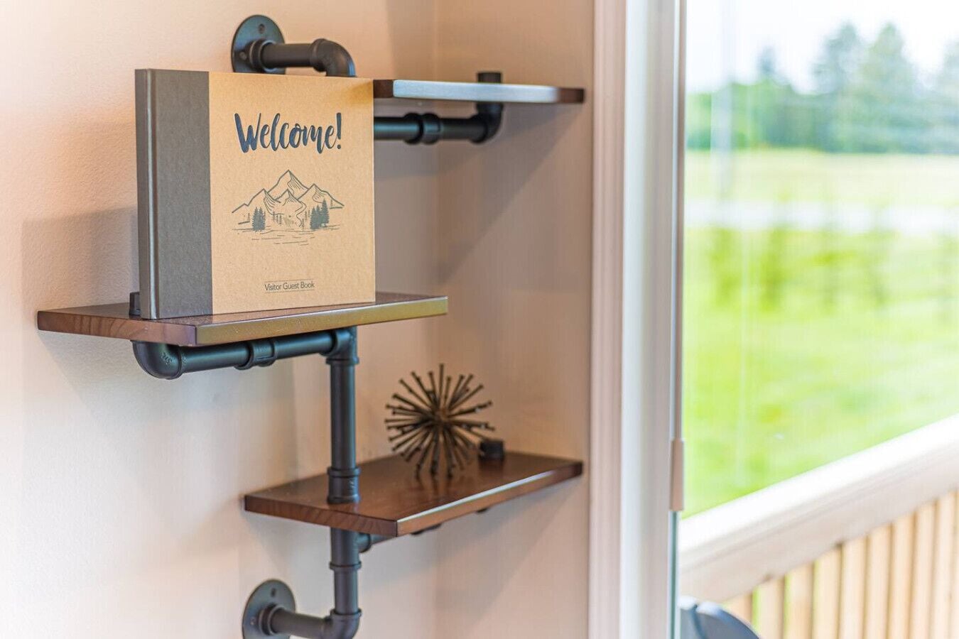 Eine Wandablage mit einem 'Welcome!'-Schild und einem 'Visitor Guest Book' an einer Metallrohrkonstruktion.
