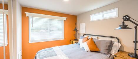 A bedroom with a bed, a nightstand, a lamp, and a window with blinds.