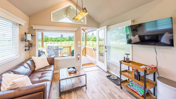 A modern living room with a leather sofa, wooden coffee table, and a TV mounted on the wall. - Rainforest Tiny Home Retreat: Industrial (Forks)