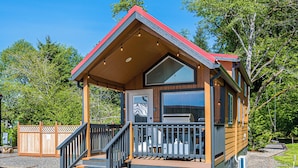 A wooden cabin with a porch, a deck, and a large window.