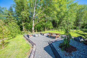 Un espace de pique-nique équipé de bancs et d’une table à pique-nique, entouré de gravier et d’arbres.