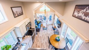 A modern kitchen with a central island, a dining area with a round table, and a cozy seating area with a blue sofa.