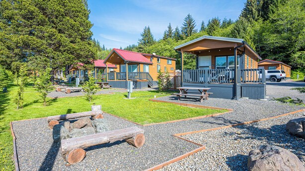 A lodge with cabins, outdoor seating, and a gravel area.