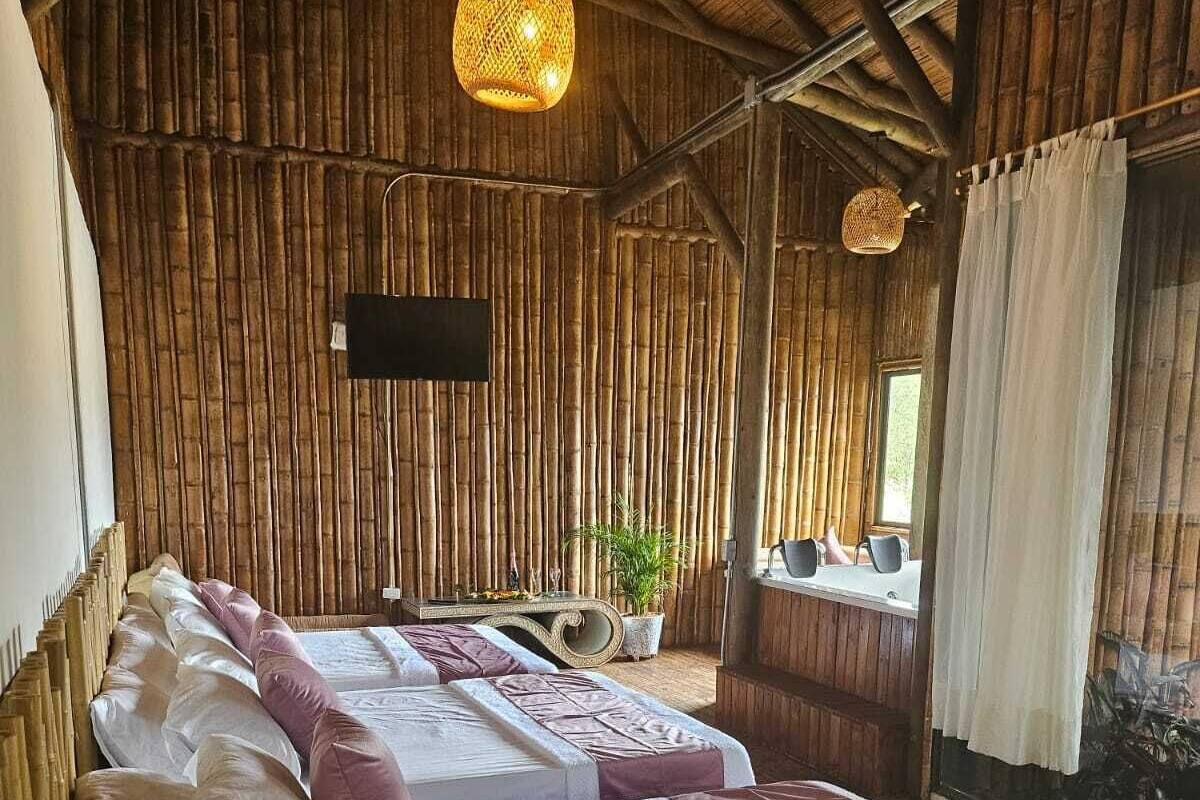 A room with a bed, a TV mounted on the wall, and a window with curtains.