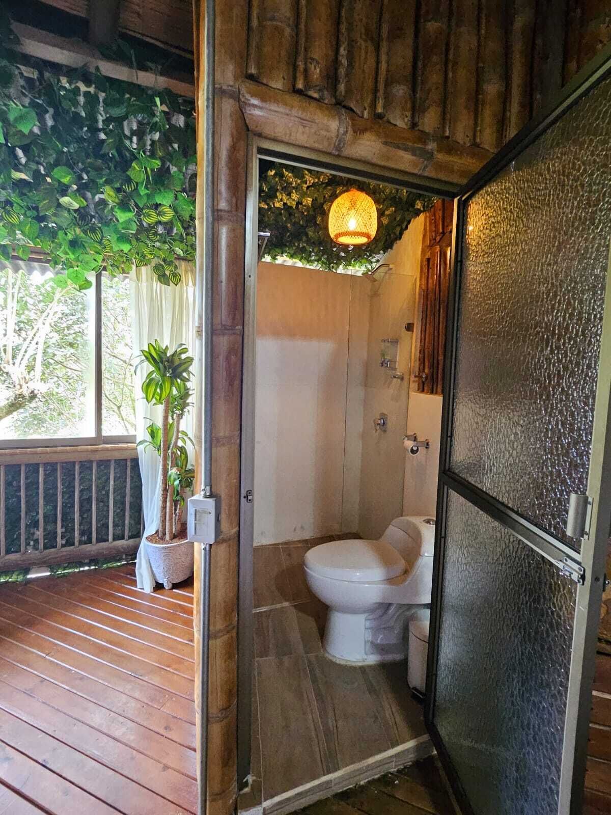 A wooden deck with potted plants, a shower area with a glass door, and a hanging light fixture.