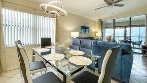 Ein modernes Wohnzimmer mit einem Glastisch, blauen Sofas und einem Deckenventilator.