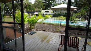 A wooden deck with a pool, surrounded by a fence and greenery. - Queen tent 10 Nelly bay (Nelly Bay)