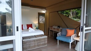 Alojamiento en tienda de campaña con cama, mesa y silla.