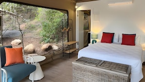 A tented room with a bed, a small table, and chairs, a view of the outdoors, and a ceiling fan. - Queen tent 10 Nelly bay (Nelly Bay)