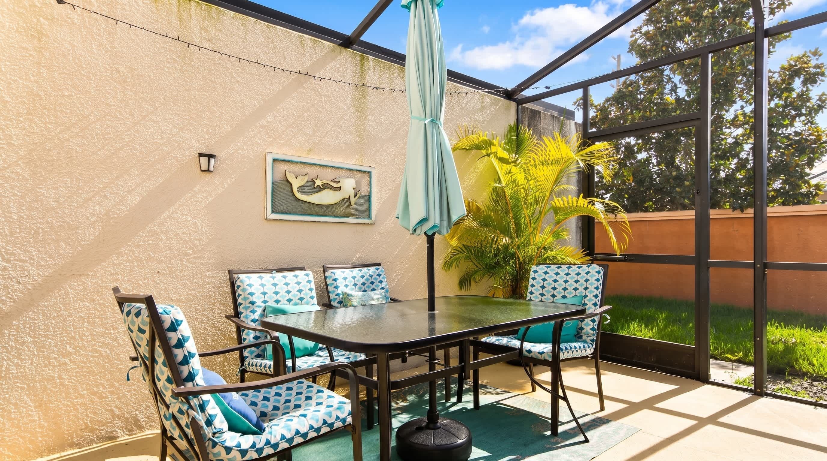 Un patio al aire libre con una mesa y sillas, un paraguas colgante y una lámpara fija en la pared.