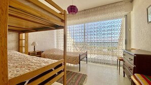Un dormitorio con una cama nido, un escritorio, una silla y un aparador.