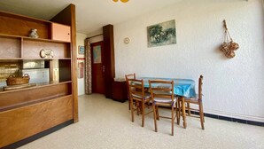 Un comedor con una mesa y sillas, un aparador de madera, un reloj y un cuadro en la pared.