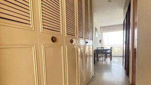 Un pasillo con puerta corredera, una zona de comedor con mesa y sillas, y una lámpara en el techo.