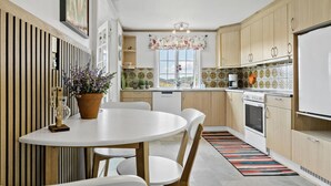 Une cuisine moderne avec une table à manger ronde, des meubles de rangement en bois et un revêtement mural coloré.
