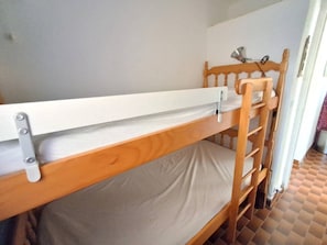 Ein Stockbett mit weißer Matratze und Holz Kopfteil.