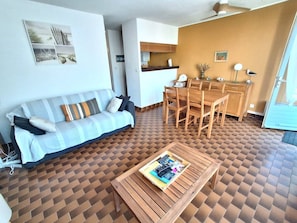 Ein Wohnzimmer mit einer Couch, einem Esstisch mit Stühlen und einem gemusterten Boden.