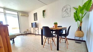 Ein modernes Wohnzimmer mit Essbereich, Fernseher und einer großen Pflanze.