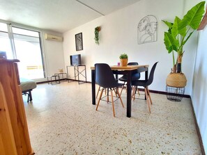 A modern living room with a dining area, a television, and a large plant.
