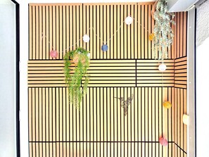 A room with a slatted wooden ceiling, a hanging plant, and a butterfly sculpture.