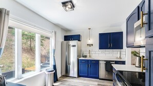A modern kitchen with blue cabinets, a stainless steel refrigerator, and a black stove. - 8-Person HotTub, Family&Group Friendly, EV Charger, Free Platinum Pool Pass (Mc Gaheysville)