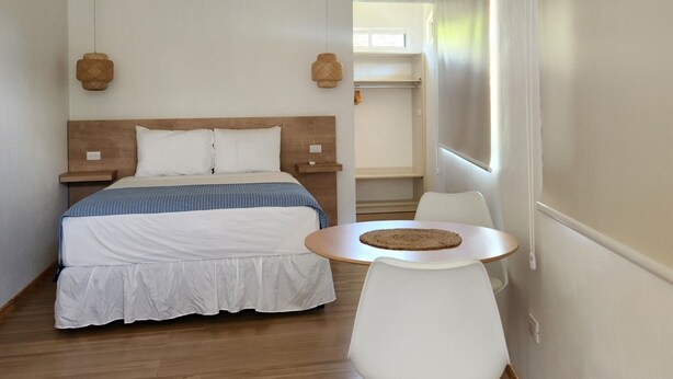 A bedroom with a bed, bedside tables, a round table with a chair, and a window.