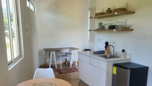 A compact kitchen with a refrigerator, a dining table with chairs, and a small island.