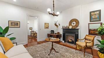 Una sala de estar con chimenea, un candelabro y un reloj grande en la pared.