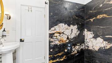 A bathroom with a white sink, a door, and black marble walls with gold veins.