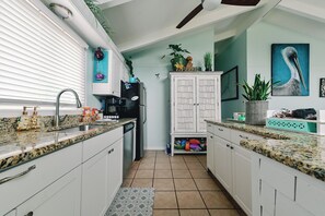 Una cocina moderna con armarios blancos, encimeras de granito, lavavajillas integrado y un refrigerador independiente.