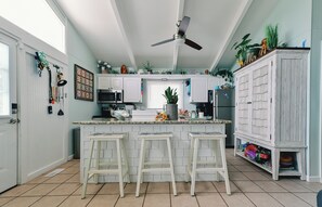 A kitchen with a central island, bar stools, a ceiling fan, and various kitchen appliances. - Convenient location in KDH with easy shopping, grocery, beach and sound access (Kill Devil Hills)