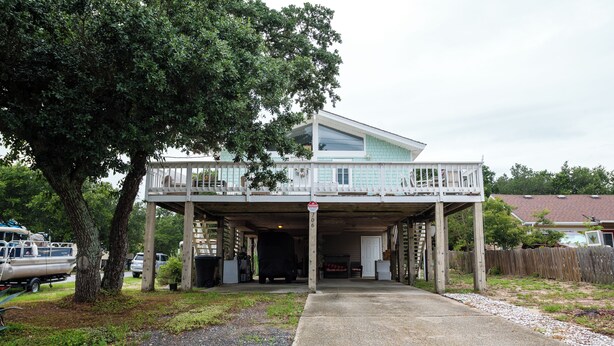 Une maison à deux étages avec un garage fermé et une véranda à l’avant.
