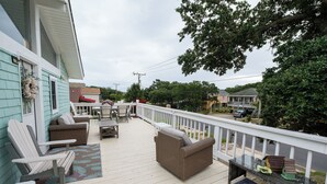 Une terrasse extérieure couverte, aménagée avec des sièges, une petite table et une nichoir.