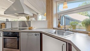 Une cuisine moderne dotée d’appareils électroménagers en acier inoxydable, d’une grande fenêtre et offrant une vue sur l’extérieur.