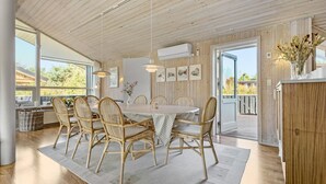 Un coin repas avec une table en bois, des chaises en osier et des œuvres d’art accrochées aux murs.