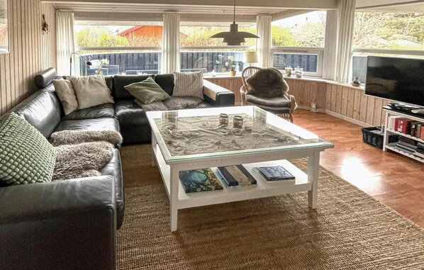 A living room with a glass coffee table, leather sofa, and a television.