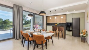 A modern kitchen with a black refrigerator, wooden cabinets, and a large window overlooking a garden. - Villa Benina Rossa Inn (Istria - Žminj) (Žminj)