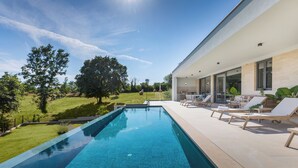 A modern outdoor pool area with clear blue water, surrounded by a well-maintained lawn and large trees. - Villa Benina Rossa Inn (Istria - Žminj) (Žminj)