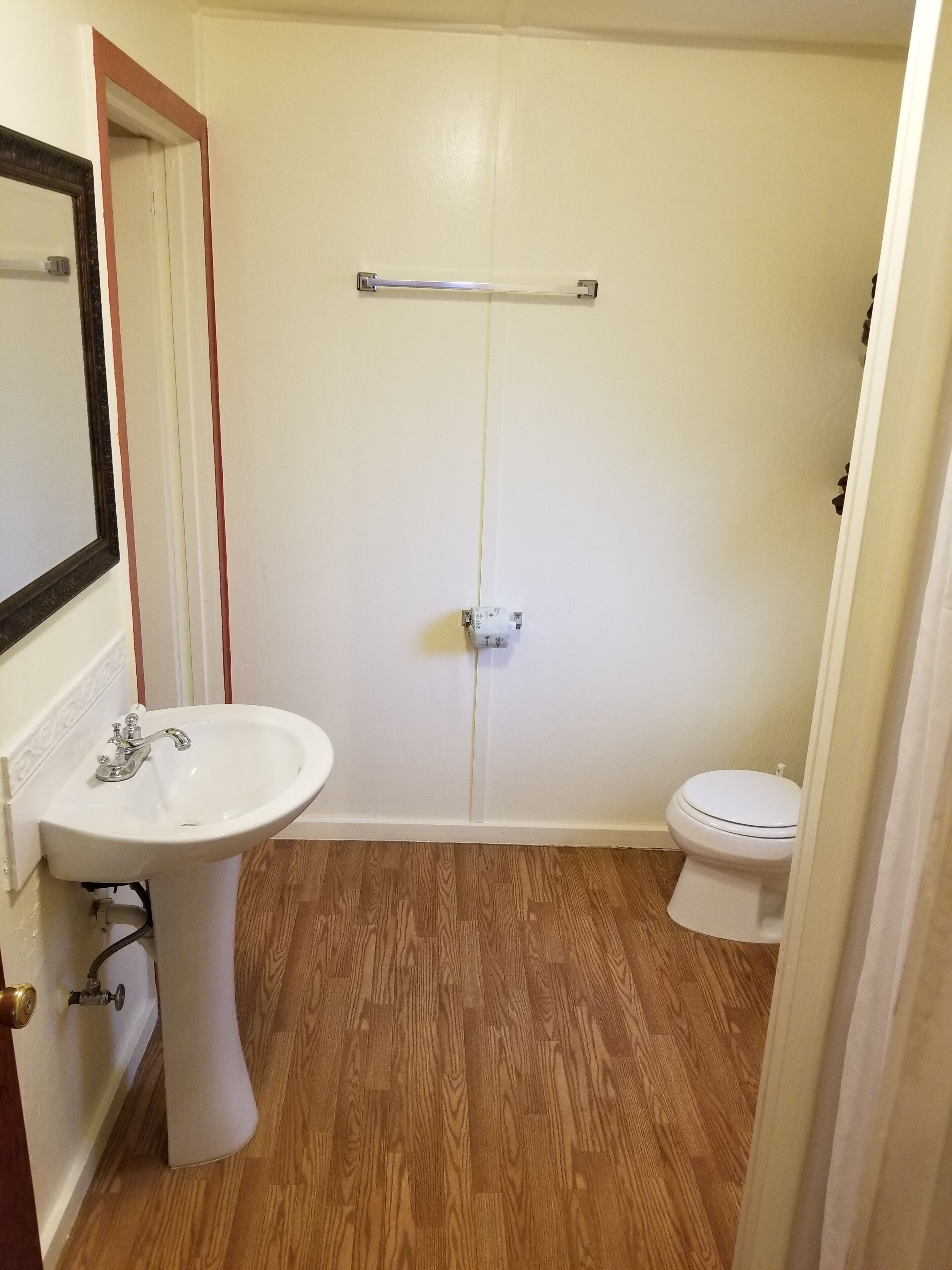 Une salle de bain avec un lavabo, des toilettes et une douche, le tout de couleur blanche.