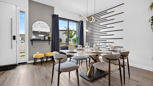 Un espace repas moderne avec une table ronde, plusieurs chaises et un élément décoratif mural.