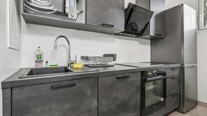 Een moderne keuken met een roestvrijstalen koelkast, oven en vaatwasser, een inbouwspoelbak en een magnetron.