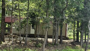 Un chalet rustique entouré d’arbres, situé dans une zone boisée.
