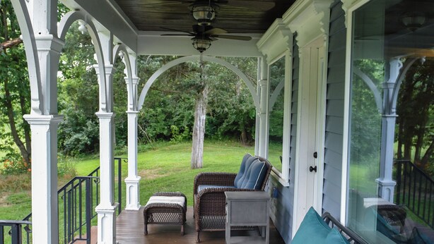 Eine überdachte Veranda mit Tisch, Bank und Sofa.